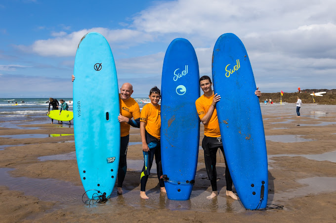 surfers stood with surfboards on Summerleaze Beach, Bude