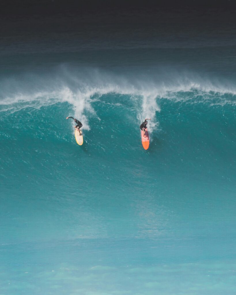 big wave. two surfers riding a large unbroken wave